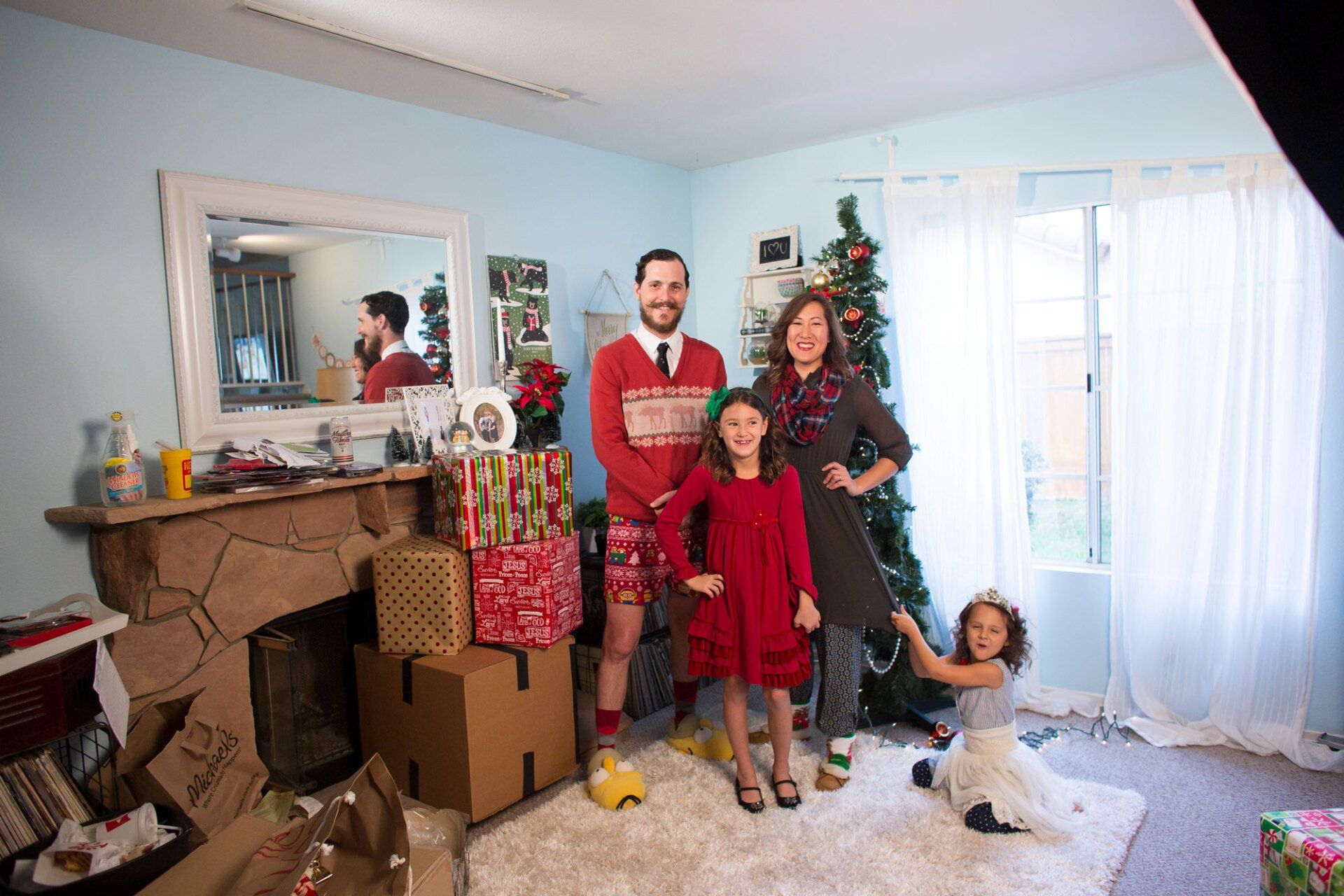 A family is posing for a picture in front of a christmas tree in a living room.