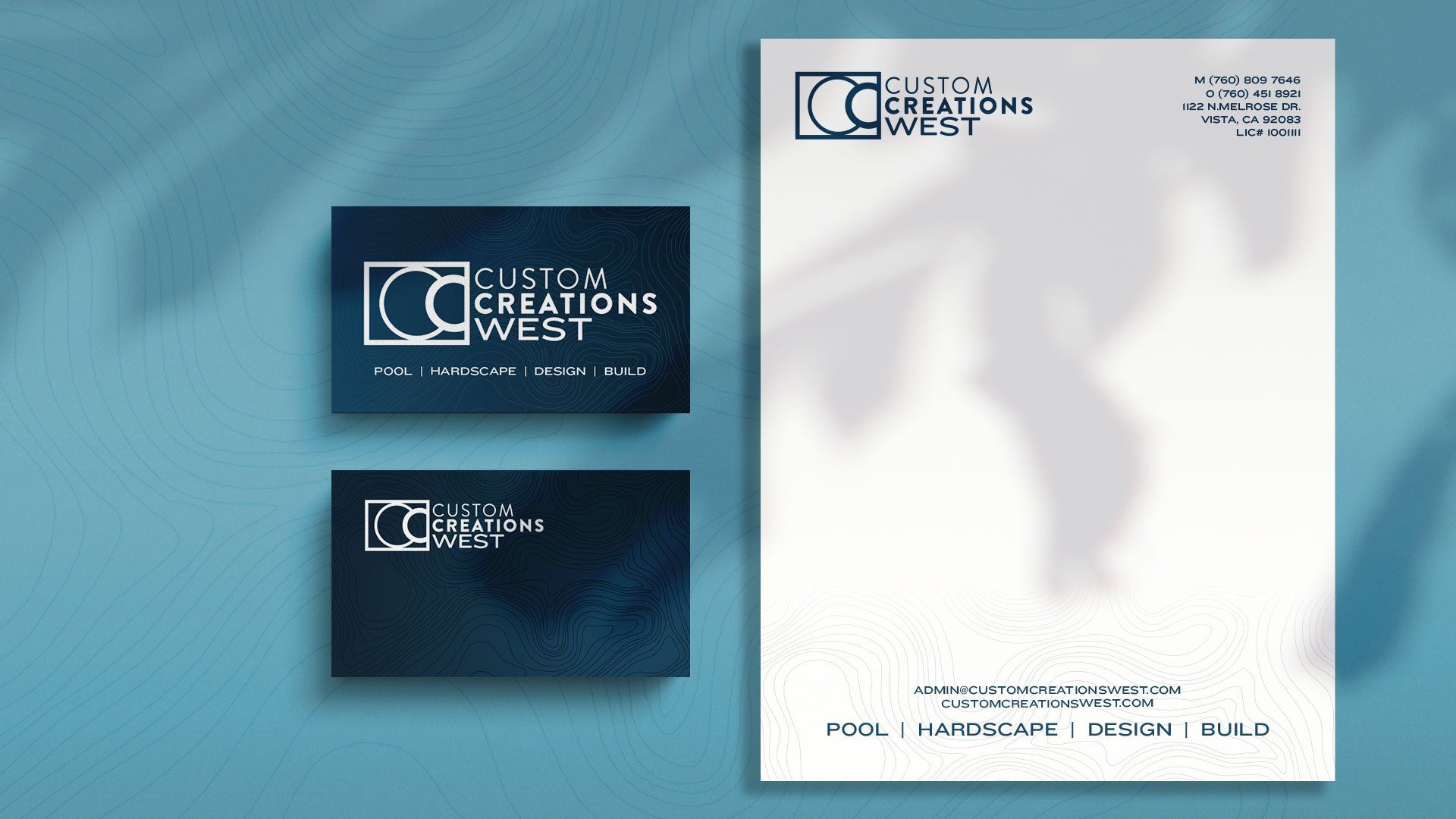 A business card and a letterhead are sitting on a blue surface.