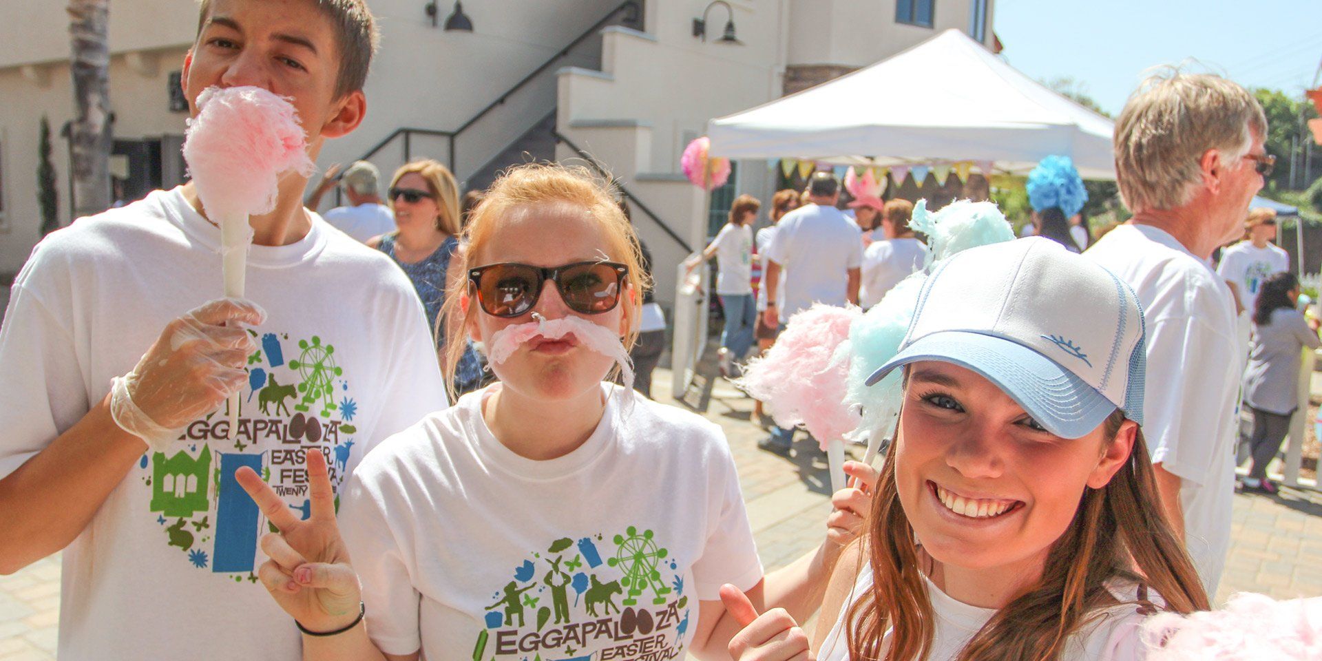 A group of people are eating cotton candy at a festival.
