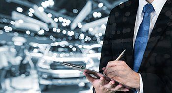 A man signing in a contract with cars in his background. A man signing in a contract with cars in his background.