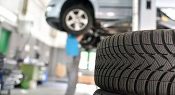 Car mechanic in a workshop, car tires in the foreground