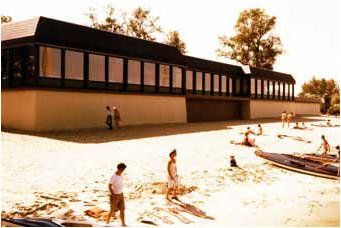 Eine Gruppe von Leuten spielt im Sand an einem Strand vor einem Gebäude.