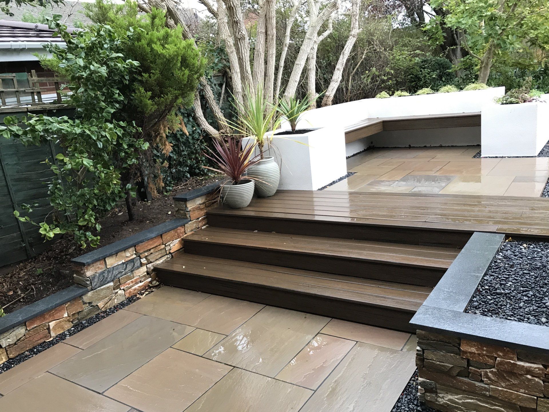 Walled paved garden up with steps up to white walled seating area