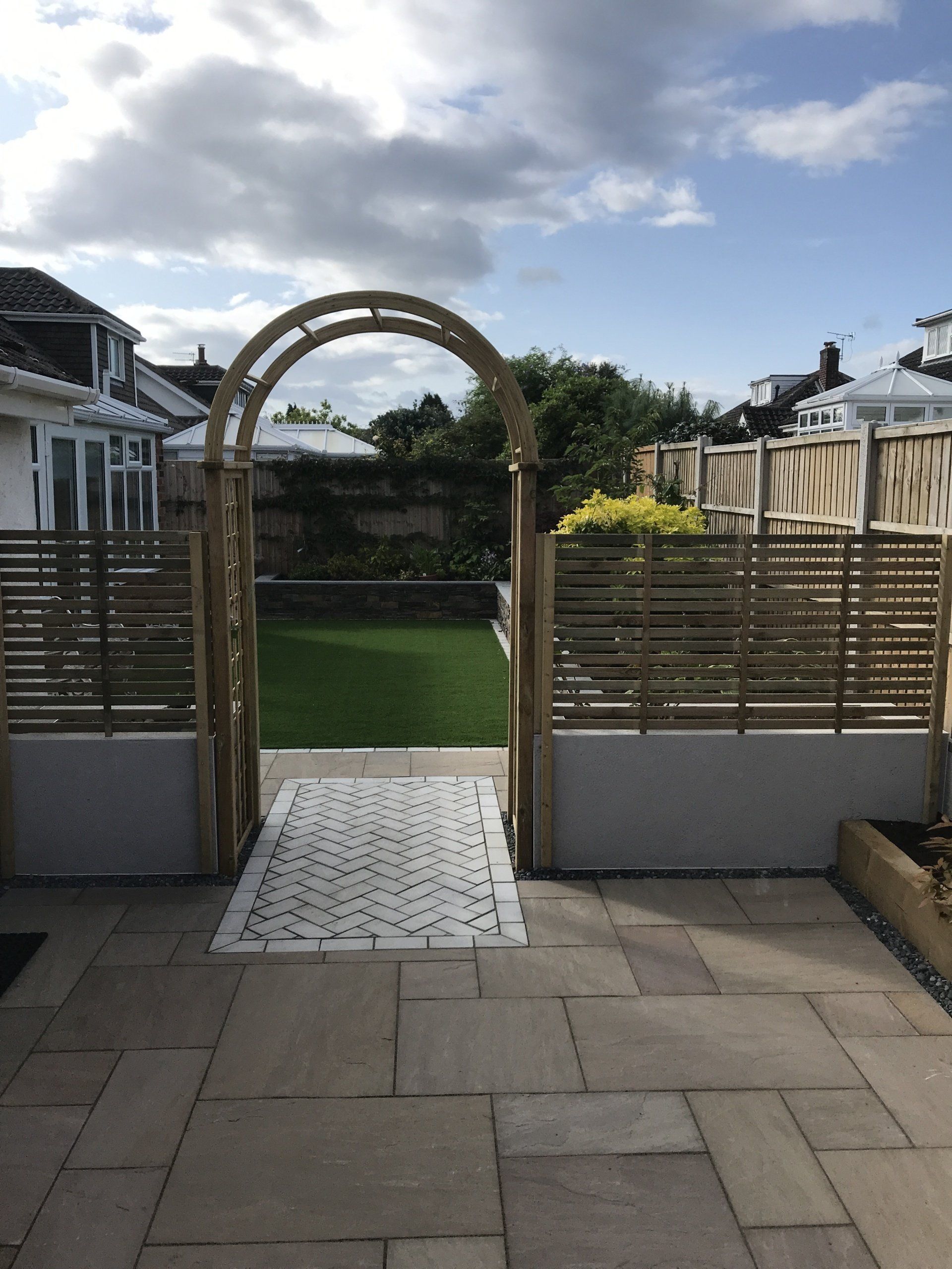 Large Pavings, fence with archway (incorporating elaborate stone work) separating patio and lawn