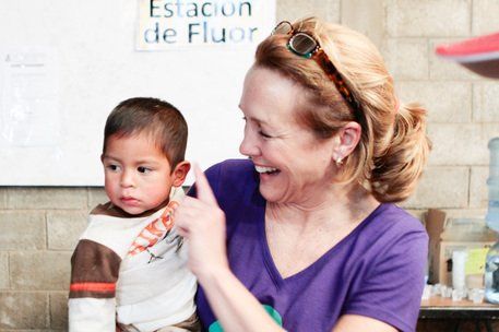 Woman smiling at a child in a clinic, pointing to his shoulder