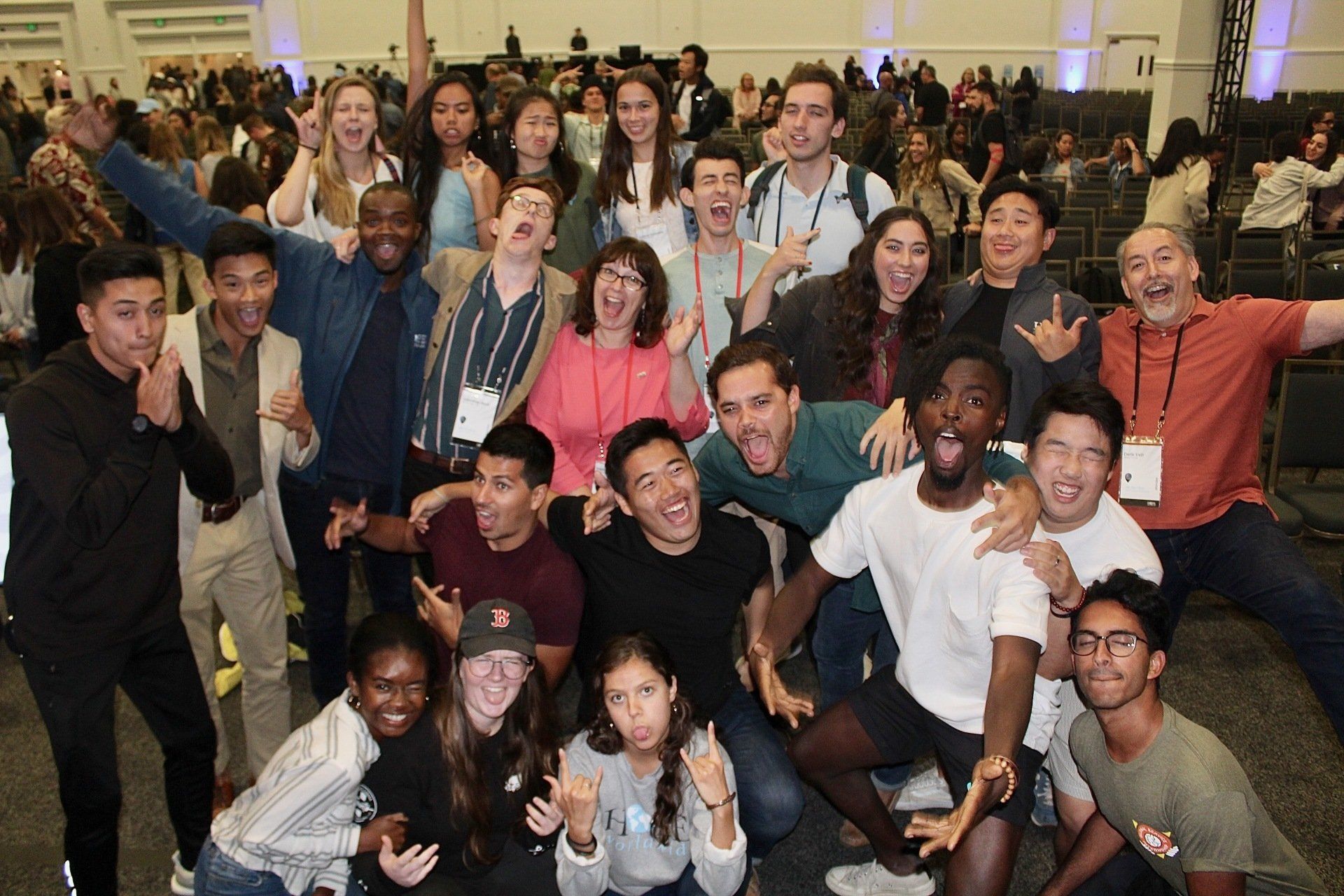Large group of people smiling and posing together indoors in a bright hall
