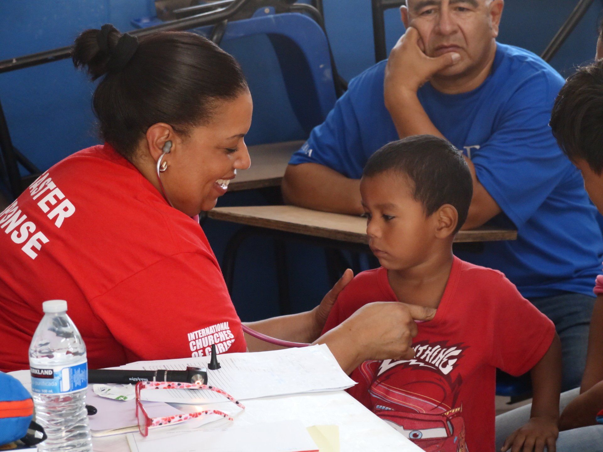 Woman in red talks with a child at a table during a community event