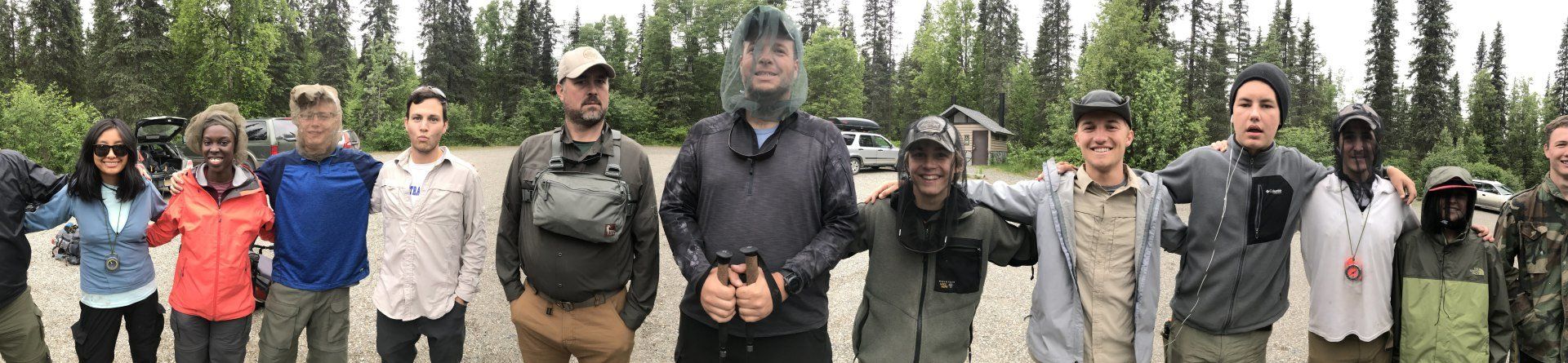 Group of hikers standing in a row outdoors in a forested mountain area