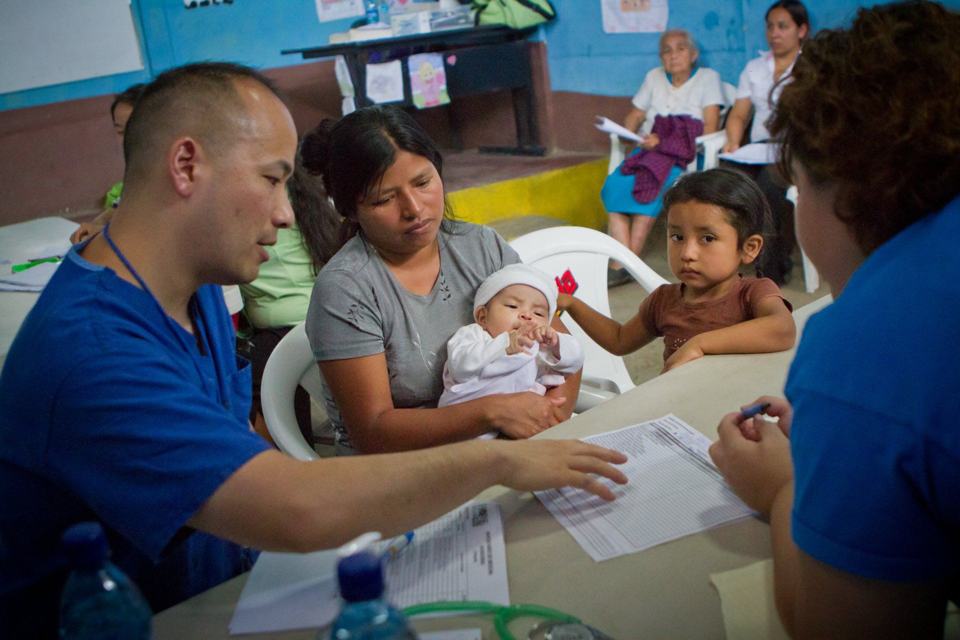 Healthcare workers meeting with a mother holding a baby in a clinic setting