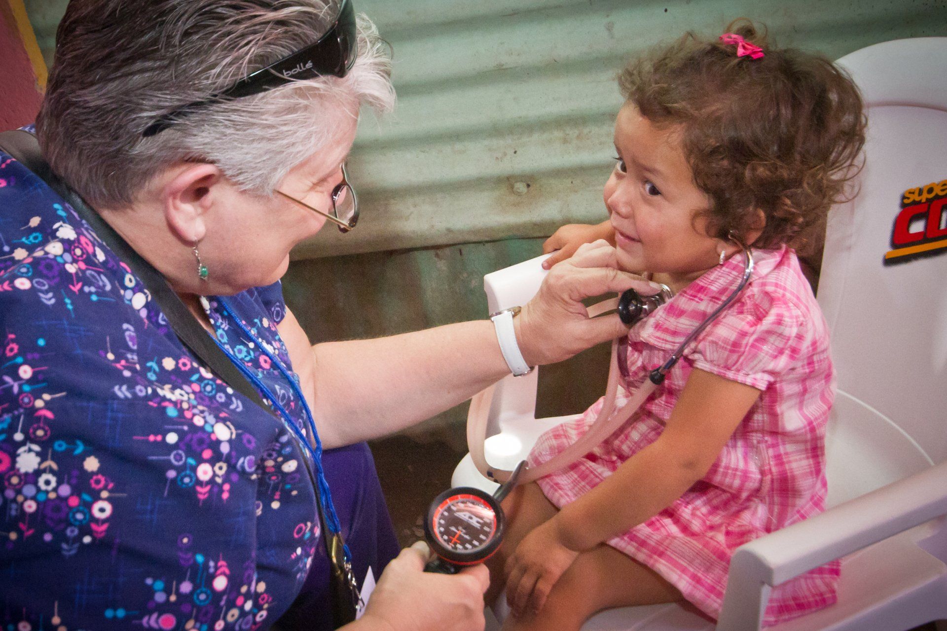 Woman examining a smiling child’s throat with a medical instrument in a clinic setting