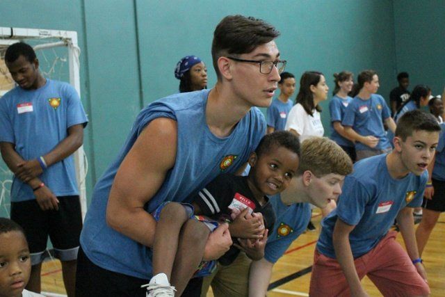 Athletes in blue shirts in a gym, leaning forward in a group workout drill