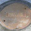 Round, weathered sewer cover with the word 