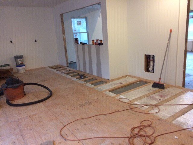 Interior room under construction, with exposed floorboards and drywall.