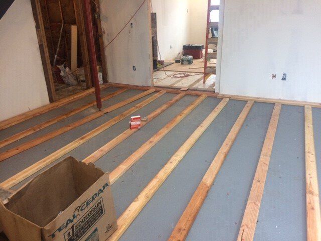 Interior construction: Wood floor joists laid over gray underlayment. Unfinished walls, open doorway.