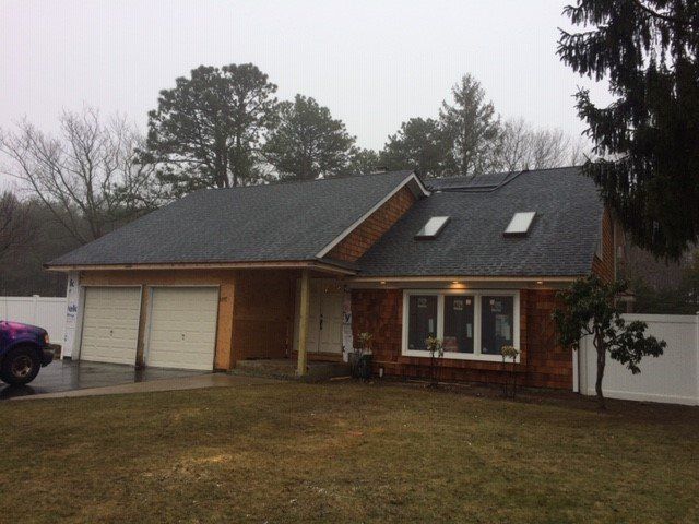 House exterior with a new roof and unfinished garage, on a cloudy day.