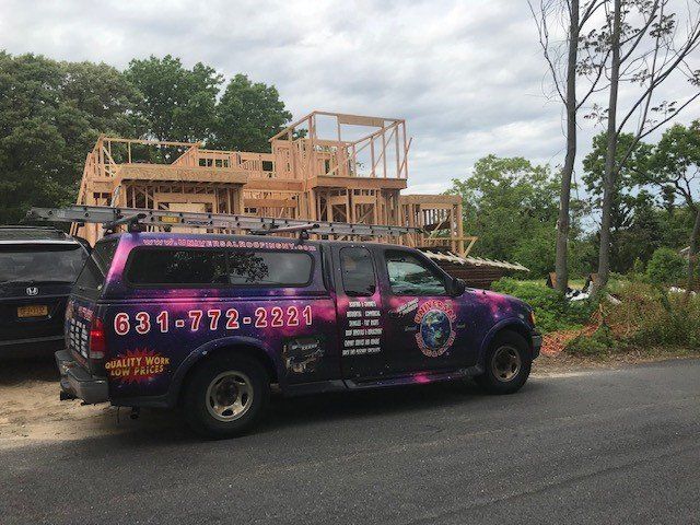 Truck with colorful galaxy wrap parked in front of a house under construction.