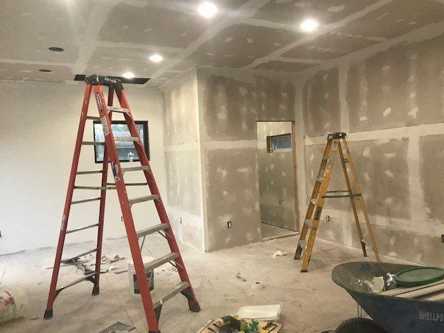 Room under construction with drywall and two step ladders.