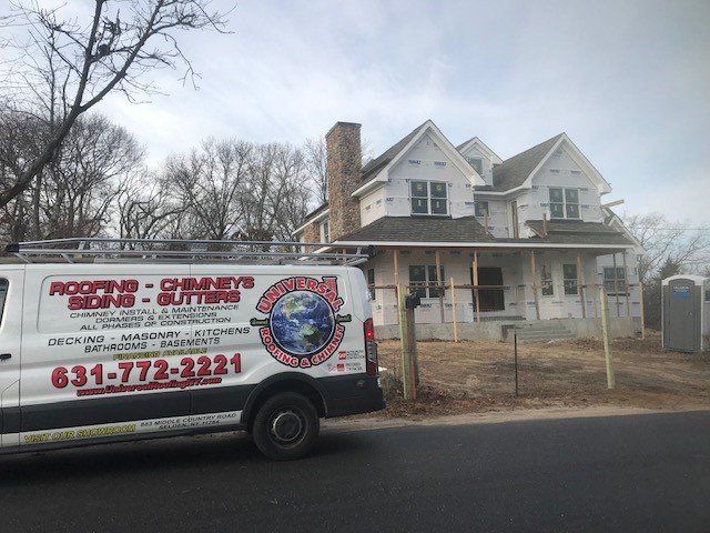 White van with roofing company logo parked near a house under construction.