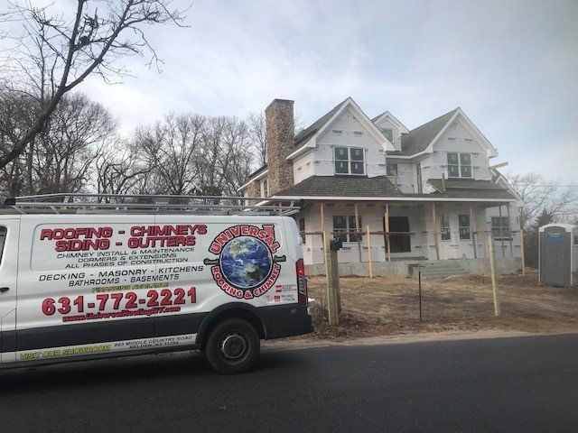 White van with company logo parked in front of a house under construction.