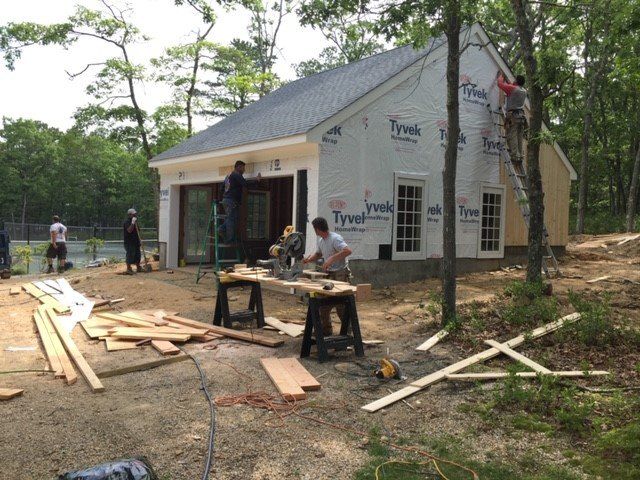 Construction site: men working on a building, cutting wood, and installing siding.