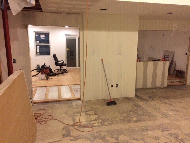 Interior renovation in progress, featuring doorways, drywall, flooring, and tools.