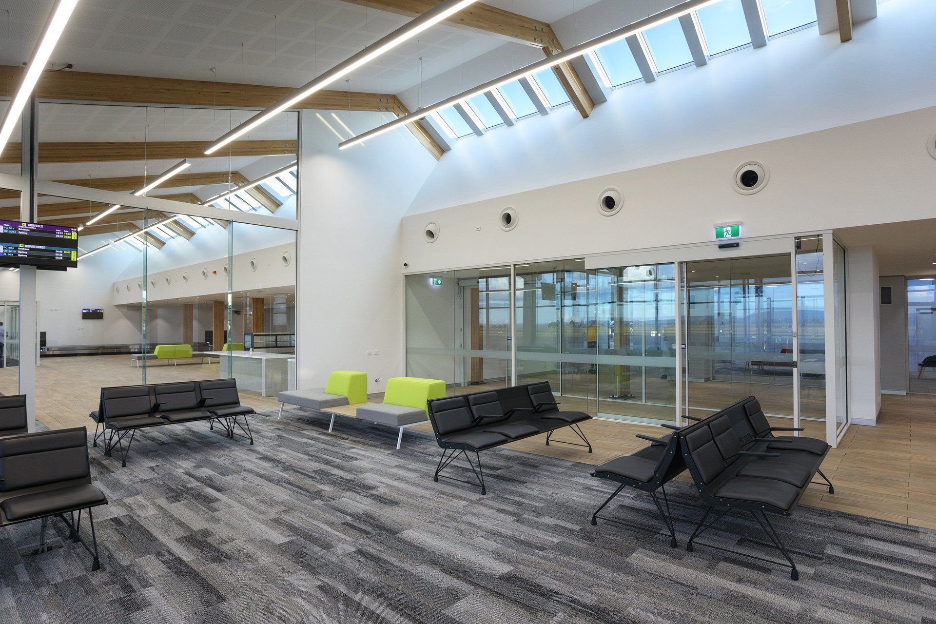 a waiting room at armidale airport with a lot of chairs and tables .