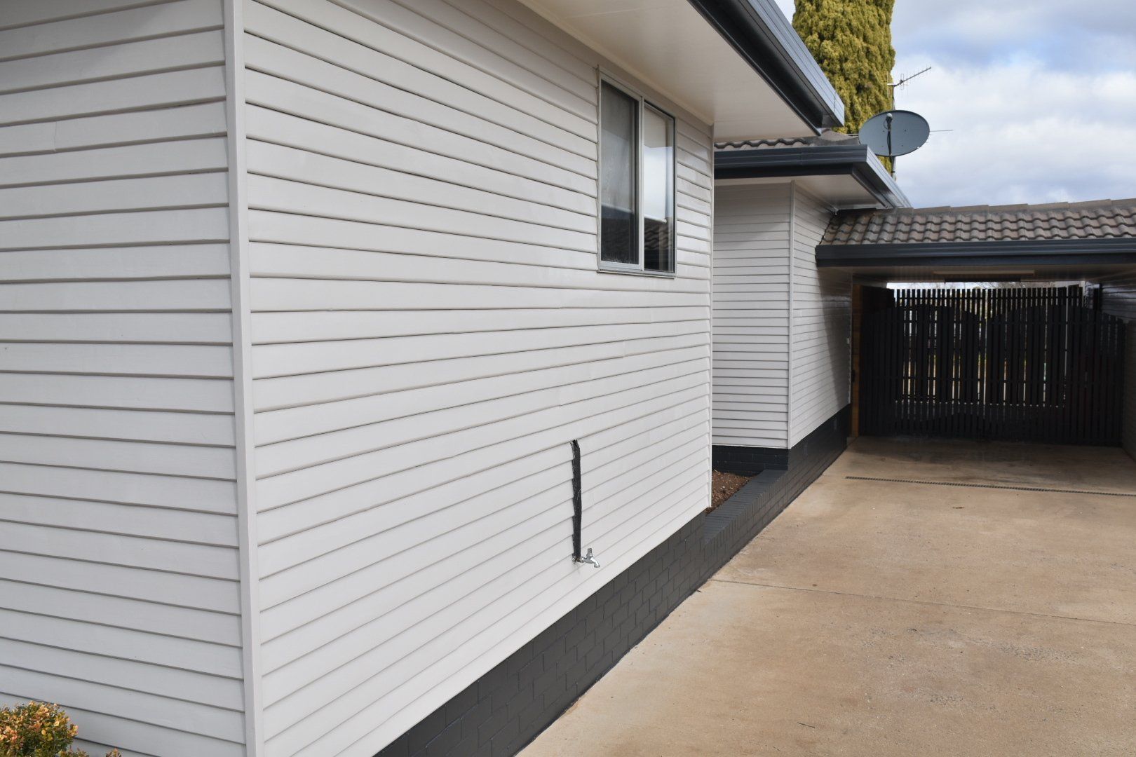 a white house with a black fence and a driveway