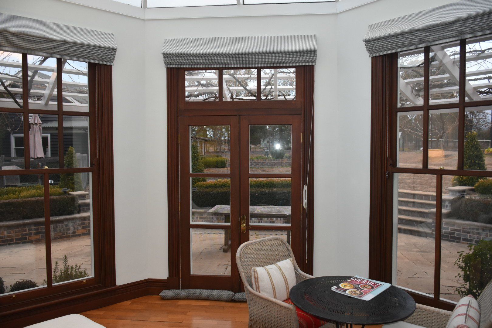 a living room with a table and chairs and lots of windows and white walls.