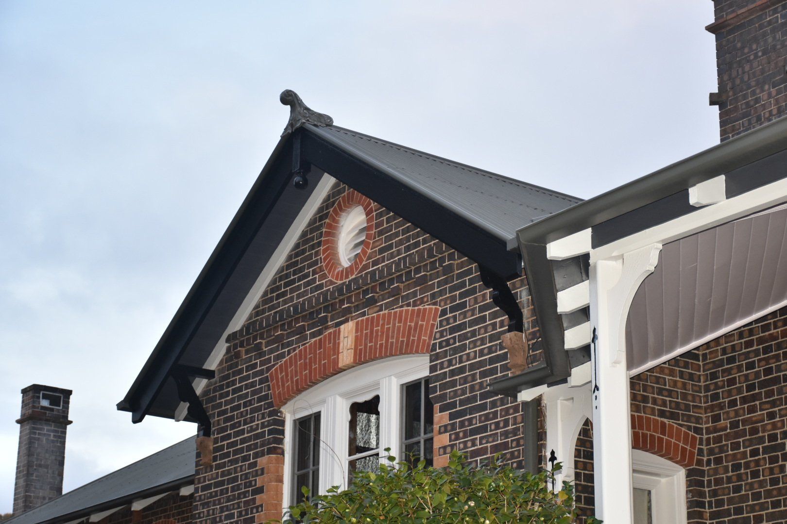 a brick building with a black roof and a white window