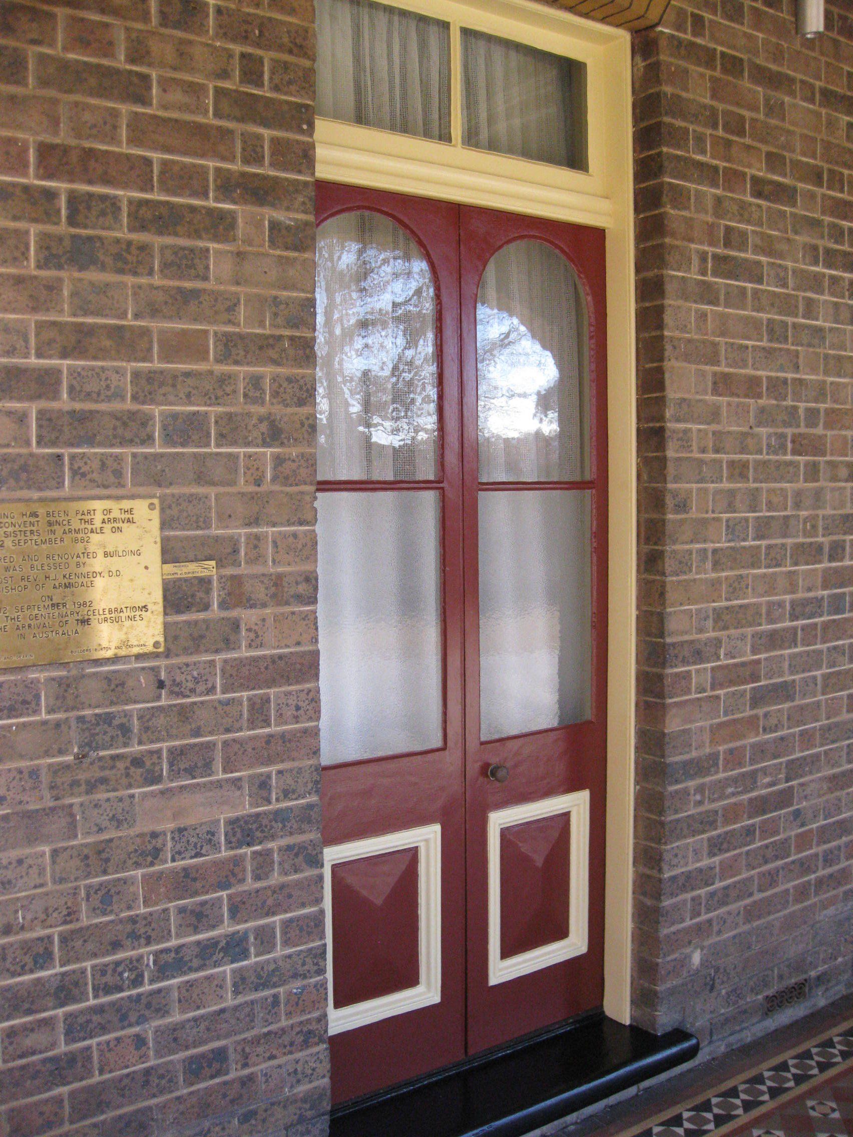 Catholic cathedral building with a red door and brass plaque on it