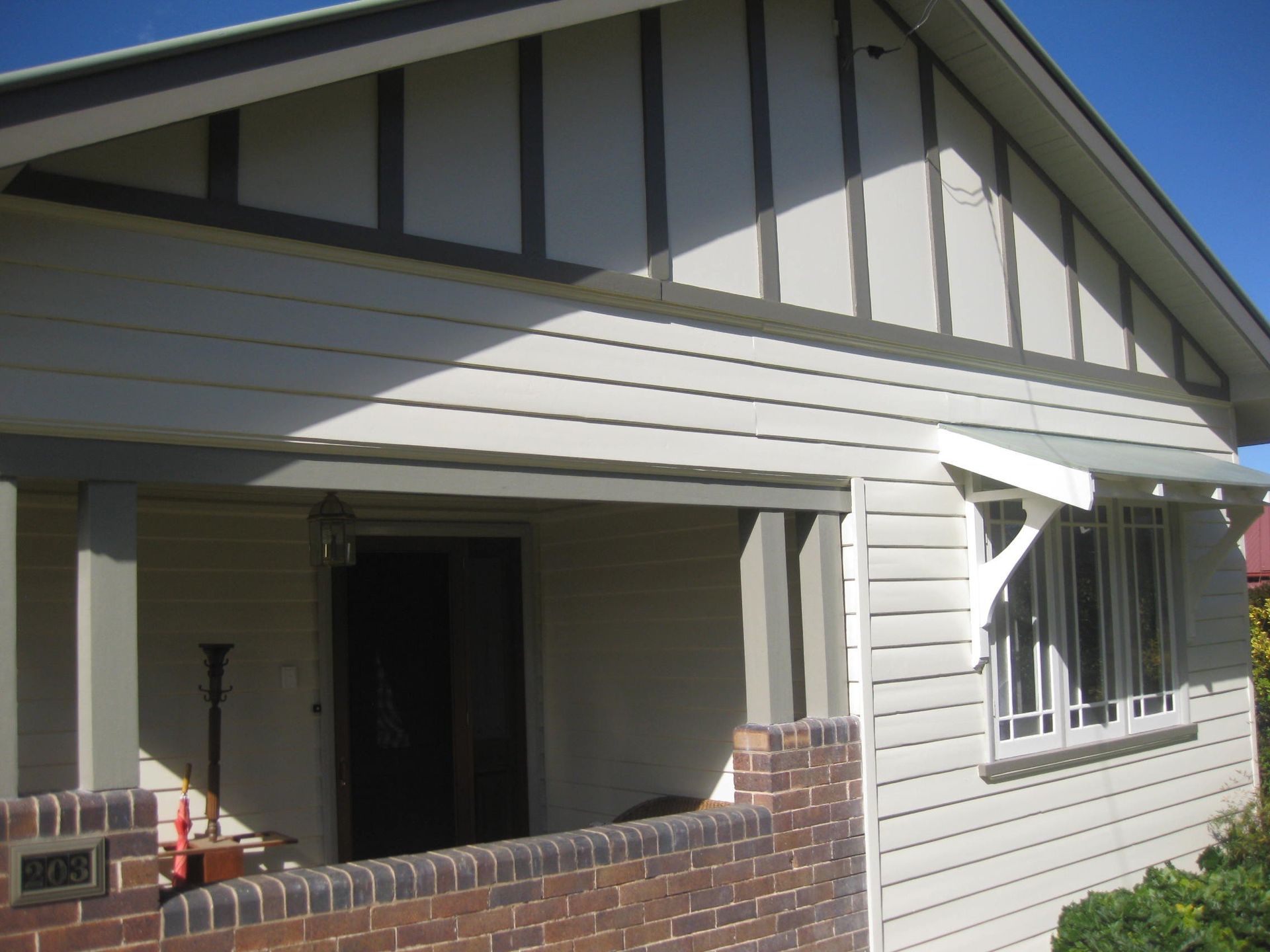 a white heritage house with a brick wall and a porch