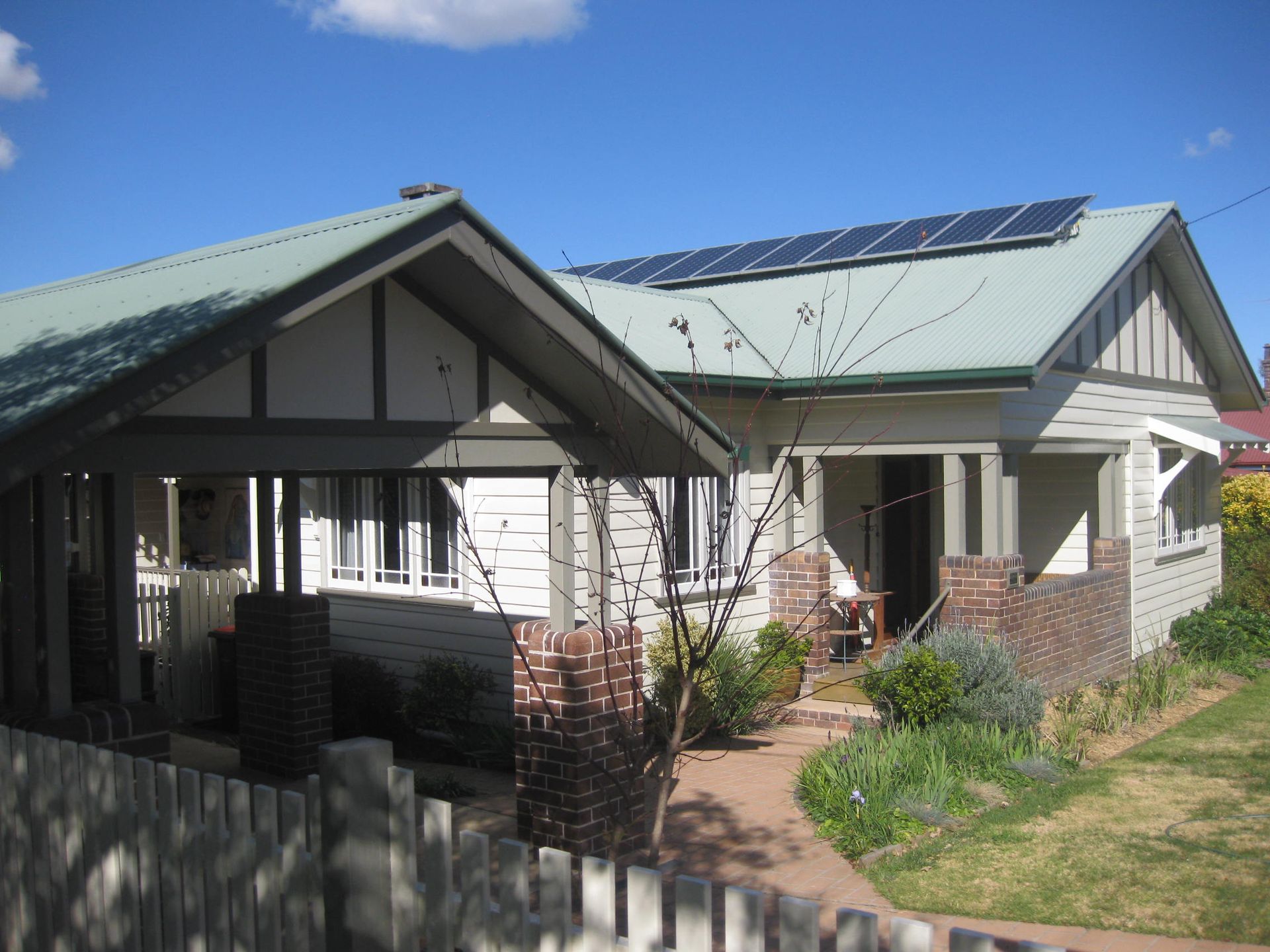 a white heritage style house with solar panels on the roof