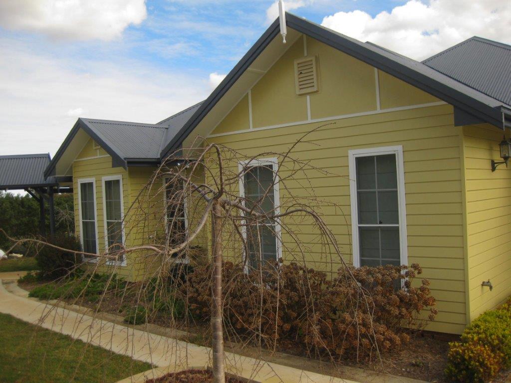 side of yellow home with windows that have white trims