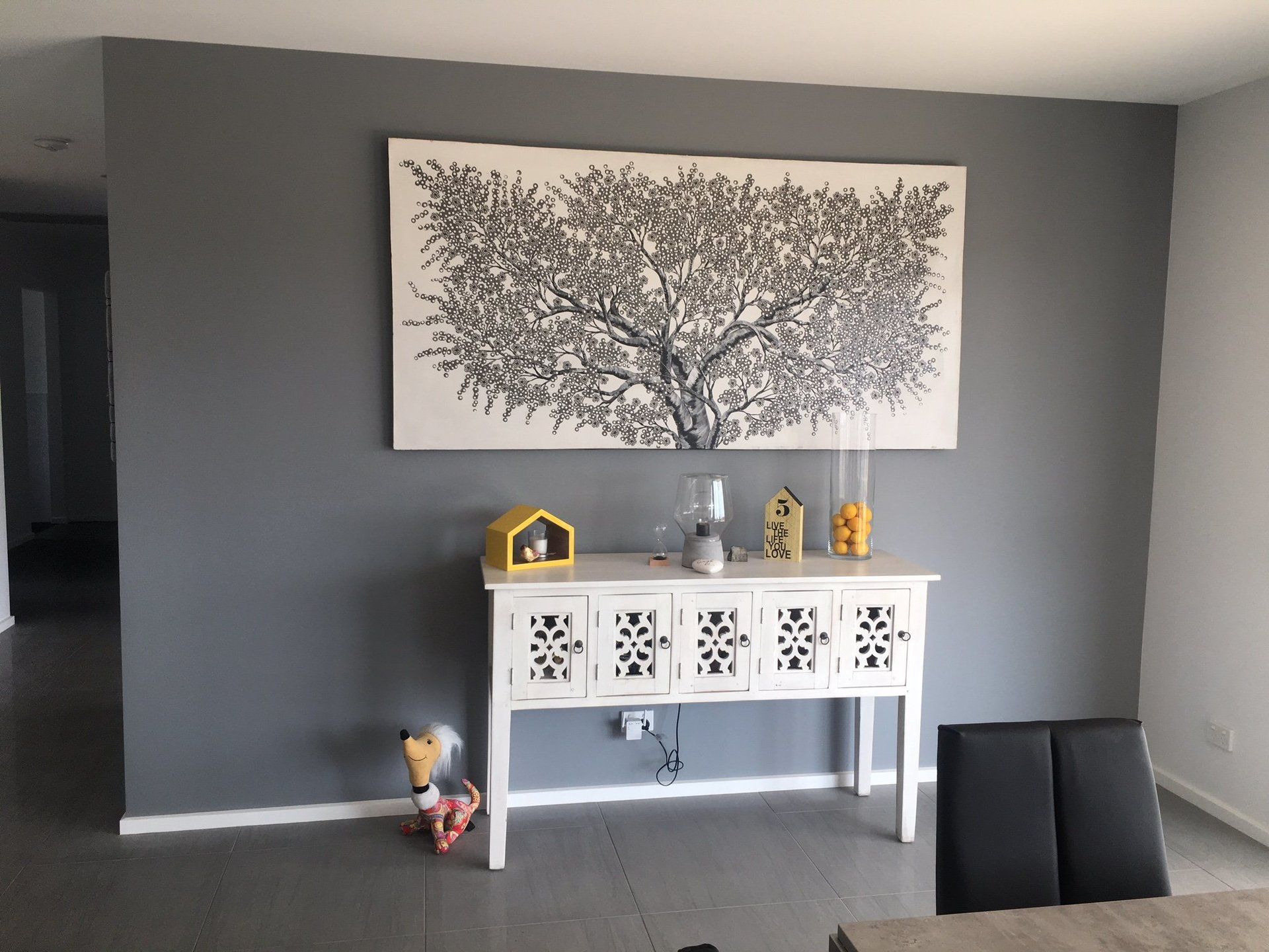 entry table and a painting on the grey painted wall above it .