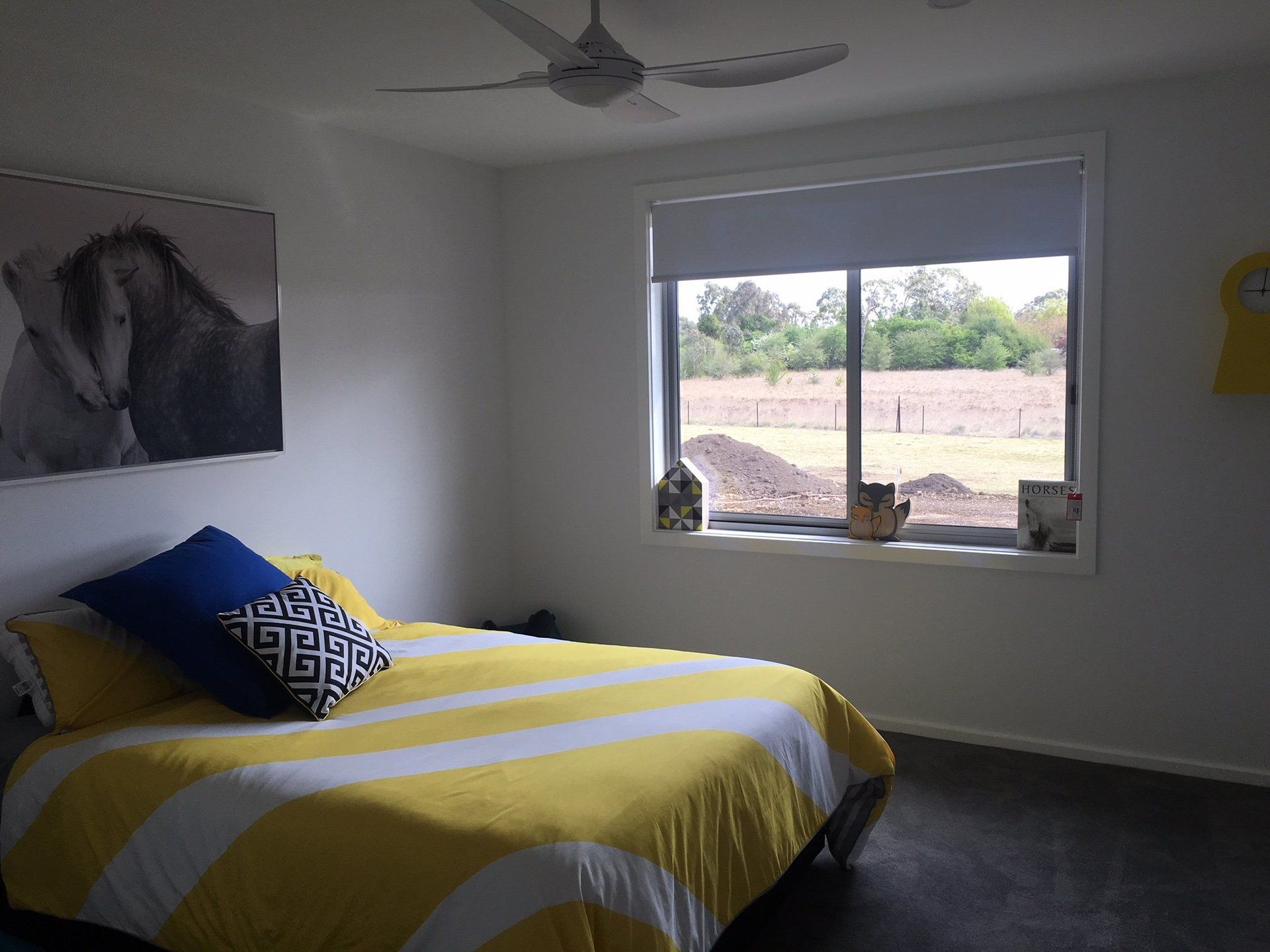 a bedroom with a bed and a window with a ceiling fan and freshly painted walls