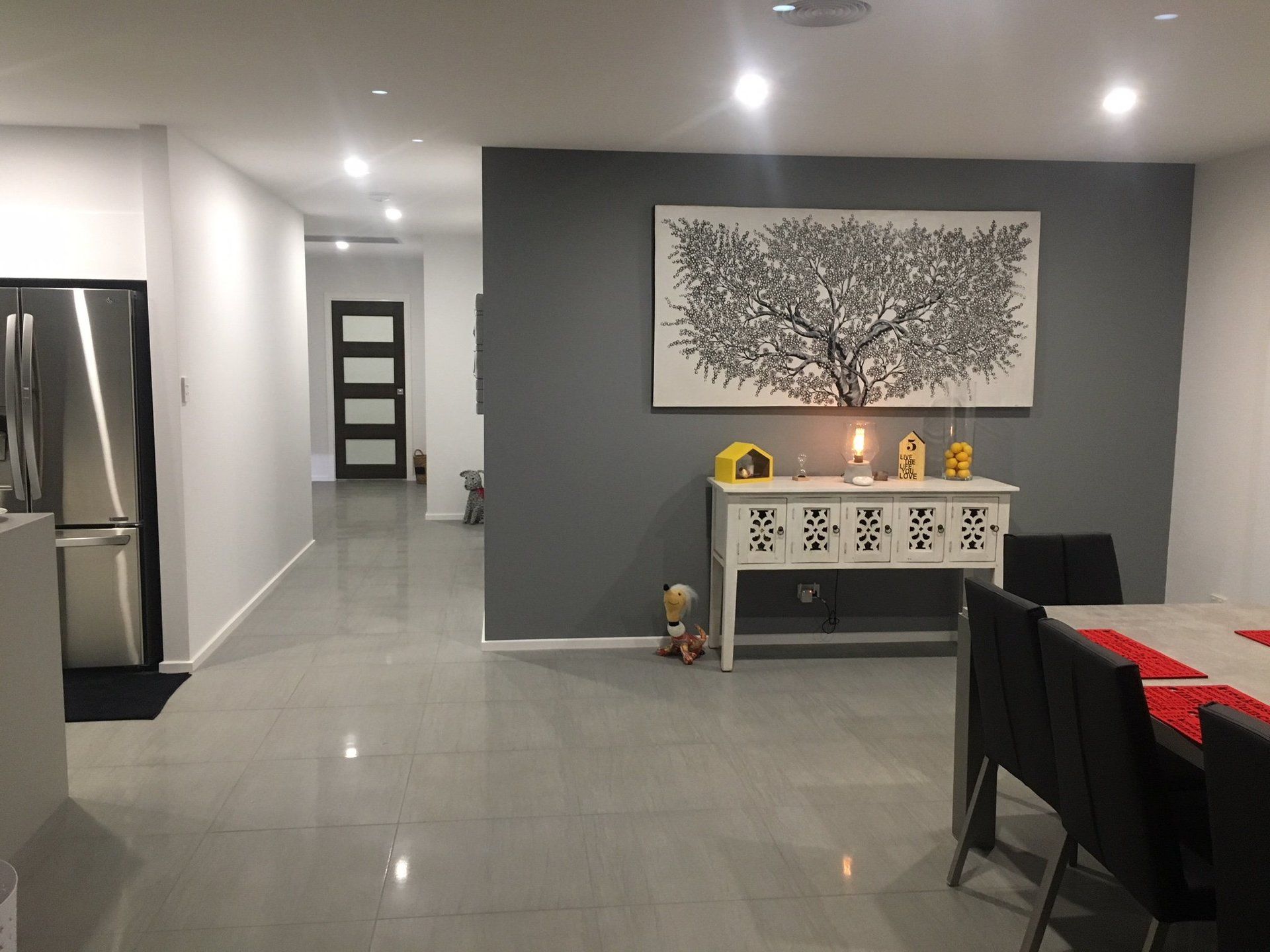 a dining room with a table and chairs and a painting on the grey feature wall