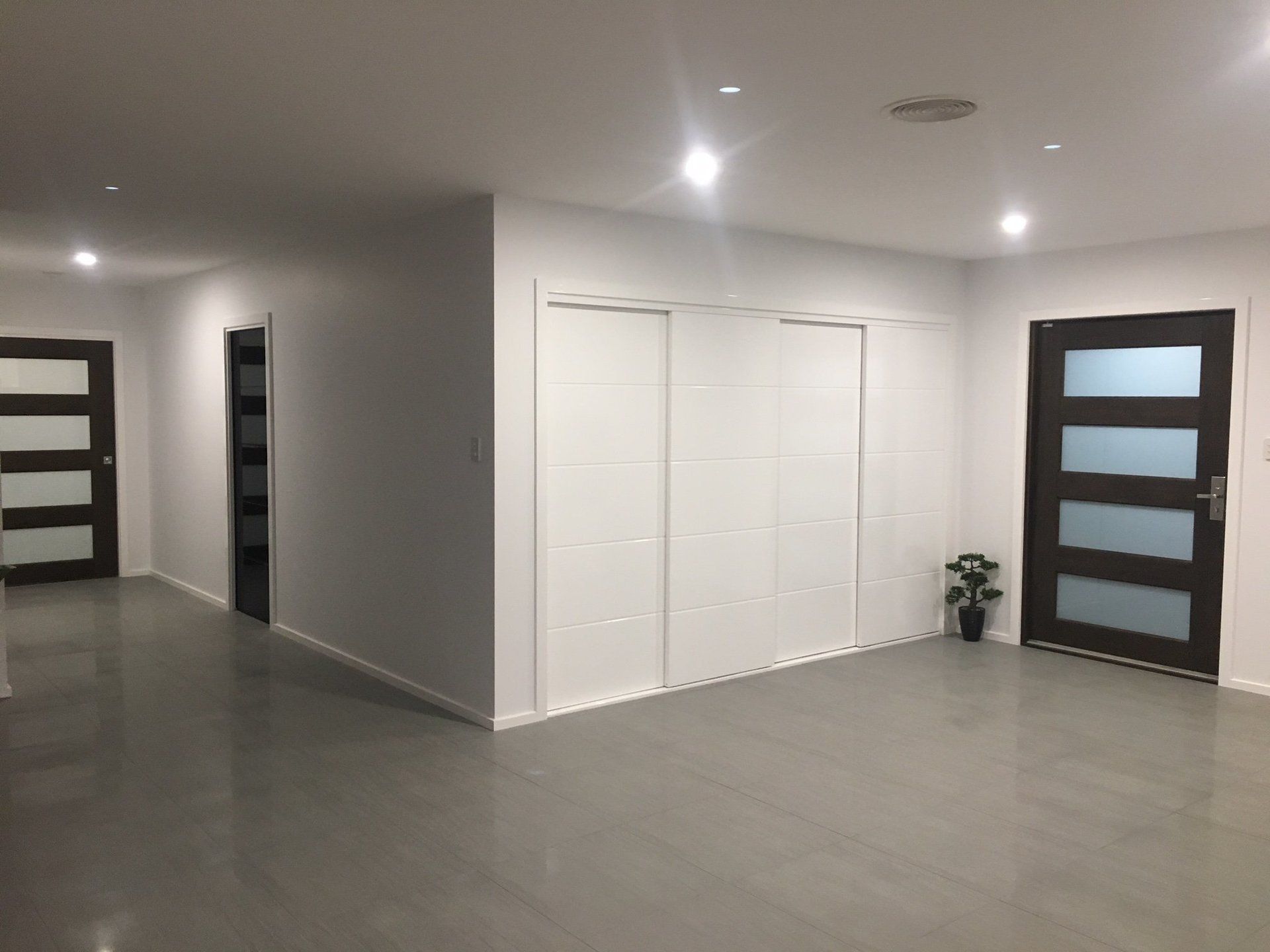 a hallway in a house with sliding glass doors and white walls .