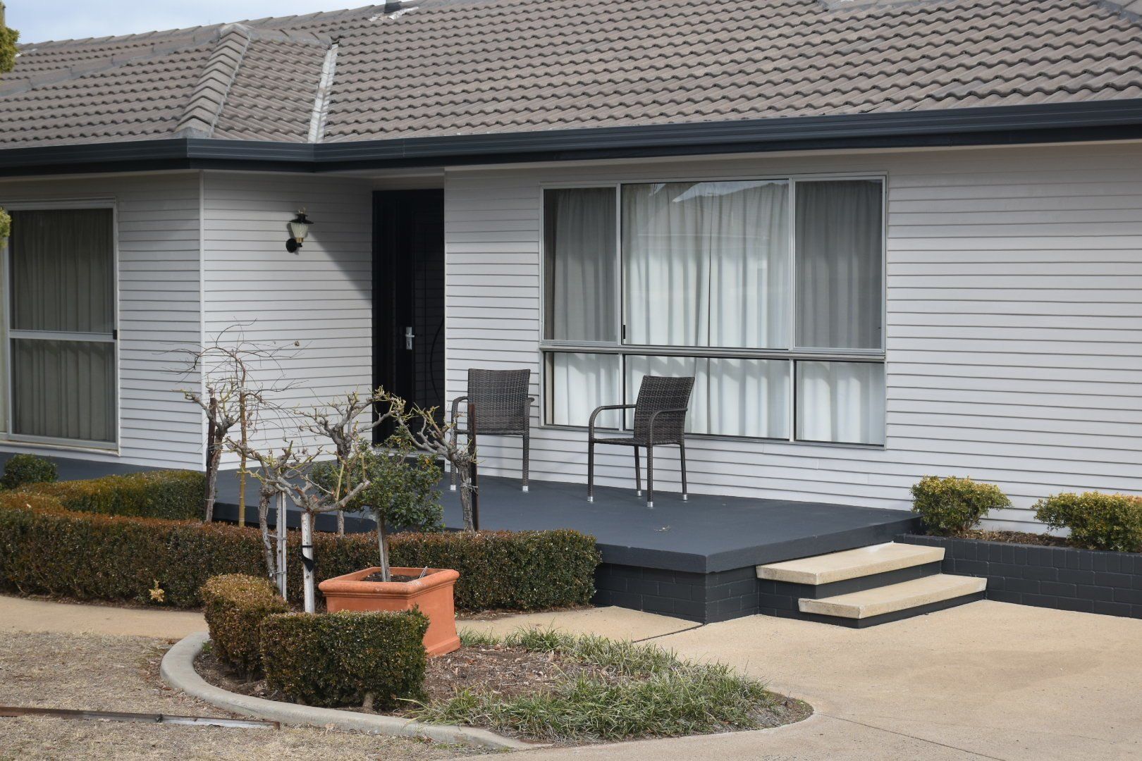 a white house with a porch and chairs in front of it