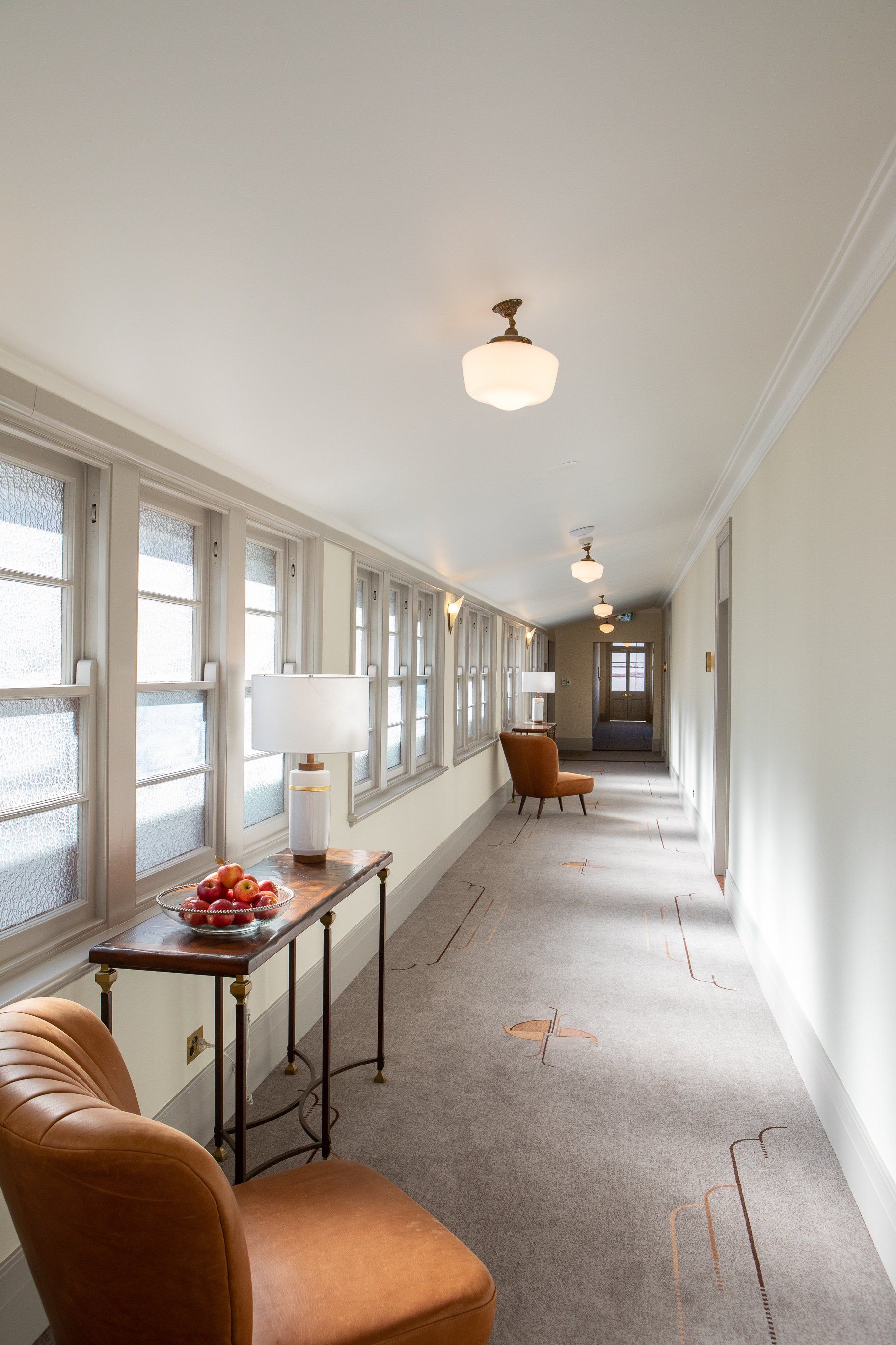 a long hallway with a table and chairs in it and cream walls