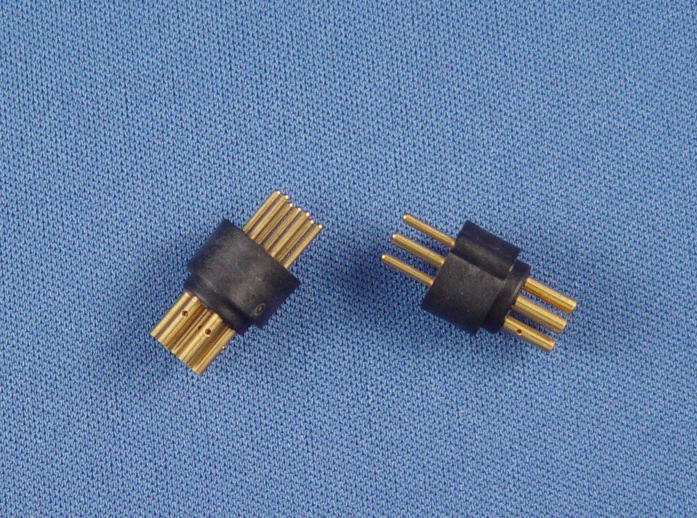 Two black and gold connectors are sitting on a blue cloth.