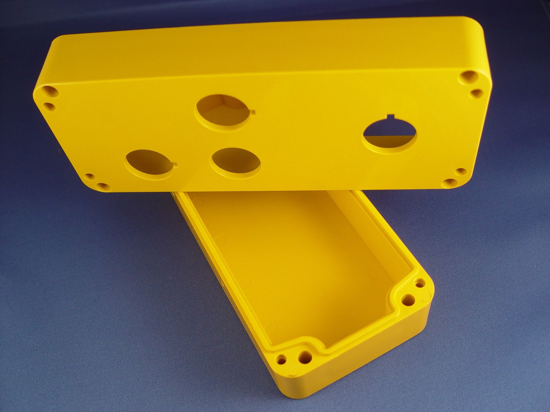 Two yellow plastic boxes with holes in them on a blue surface