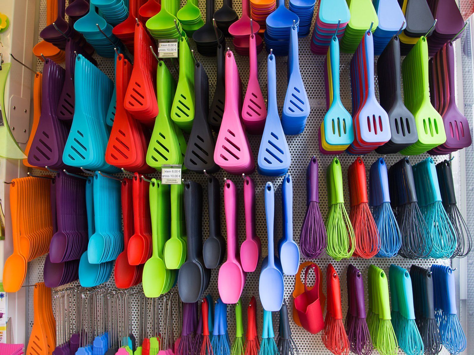 A bunch of colorful kitchen utensils hanging on a wall