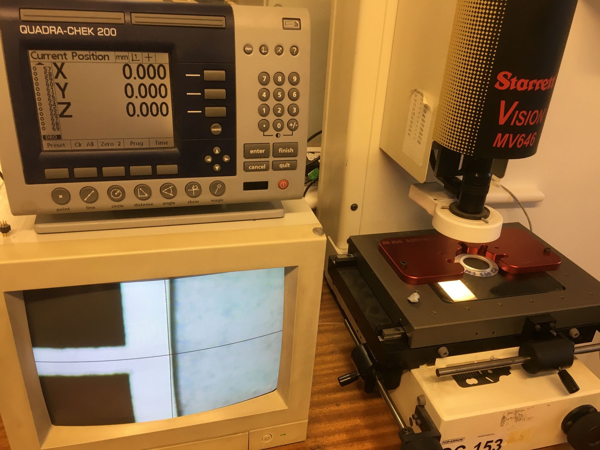 A microscope is on a table next to a computer monitor