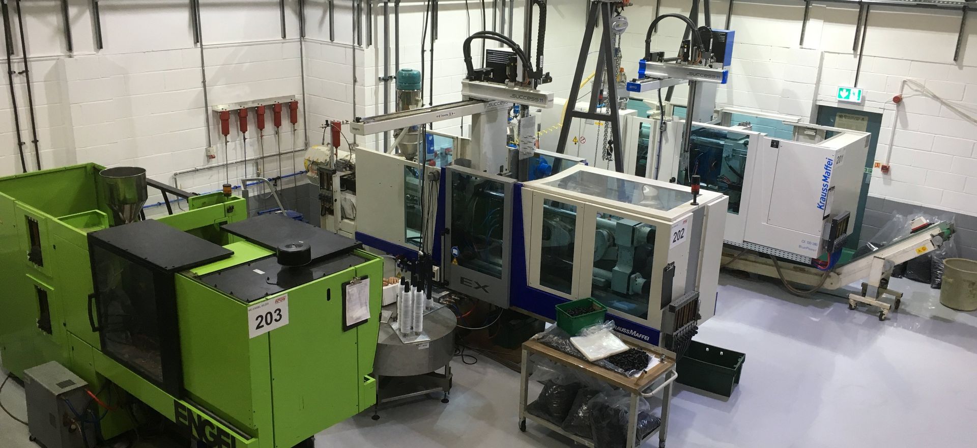 A large green machine is sitting in a factory next to a table.