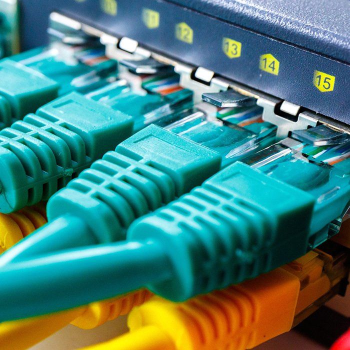 Close-up of network switch with blue and yellow ethernet cables connected to ports 13, 14, and 15.