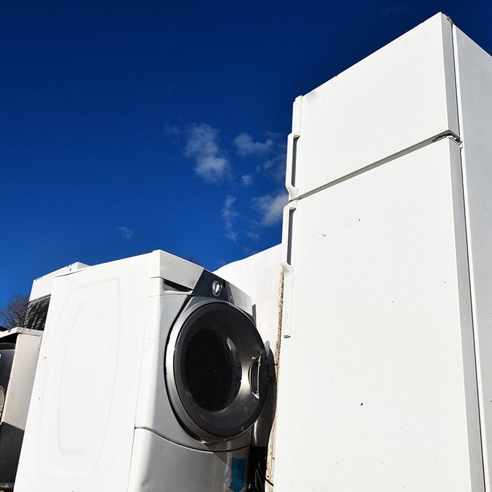 White appliances: refrigerator, washing machine, stacked against a blue sky with some clouds.