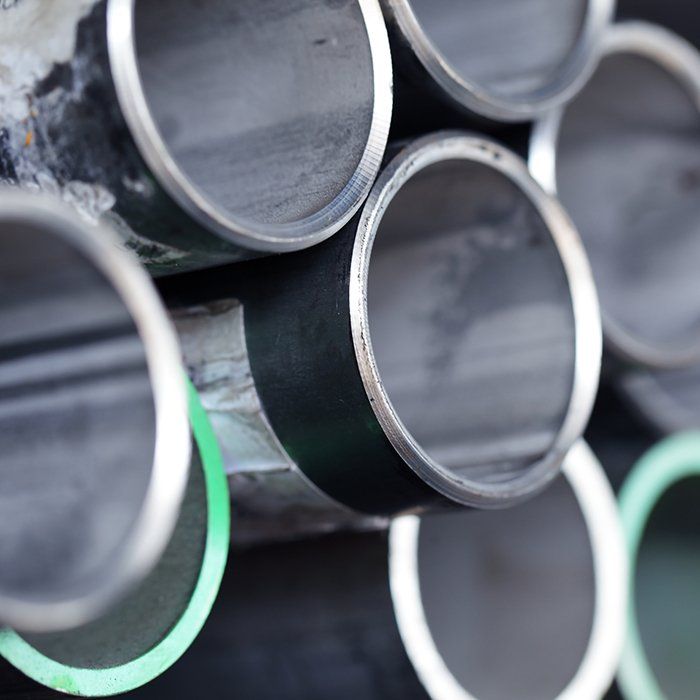 Close-up of stacked metal pipes with open ends; some painted with green or black bands.