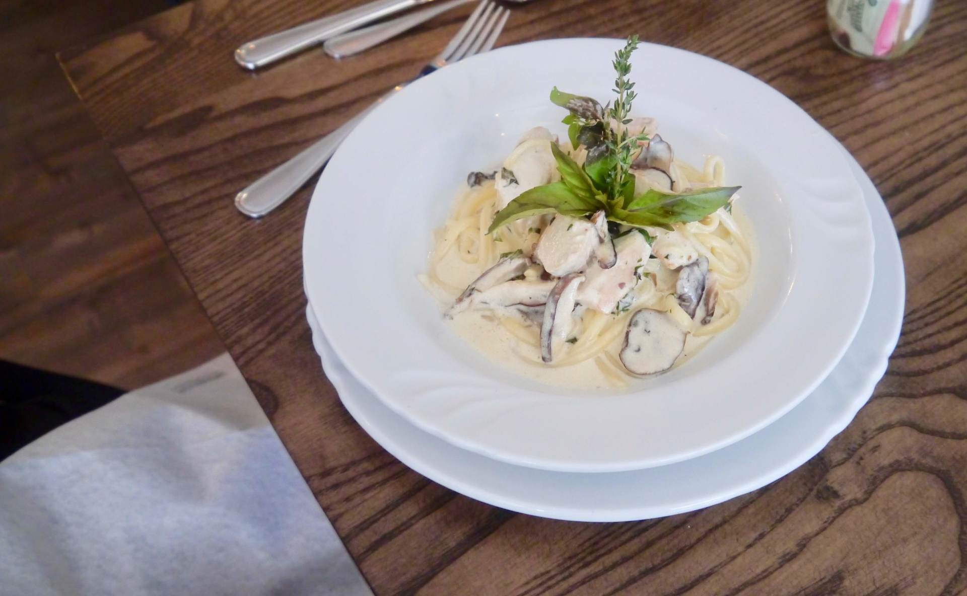 A plate of pasta with mushrooms on a wooden table