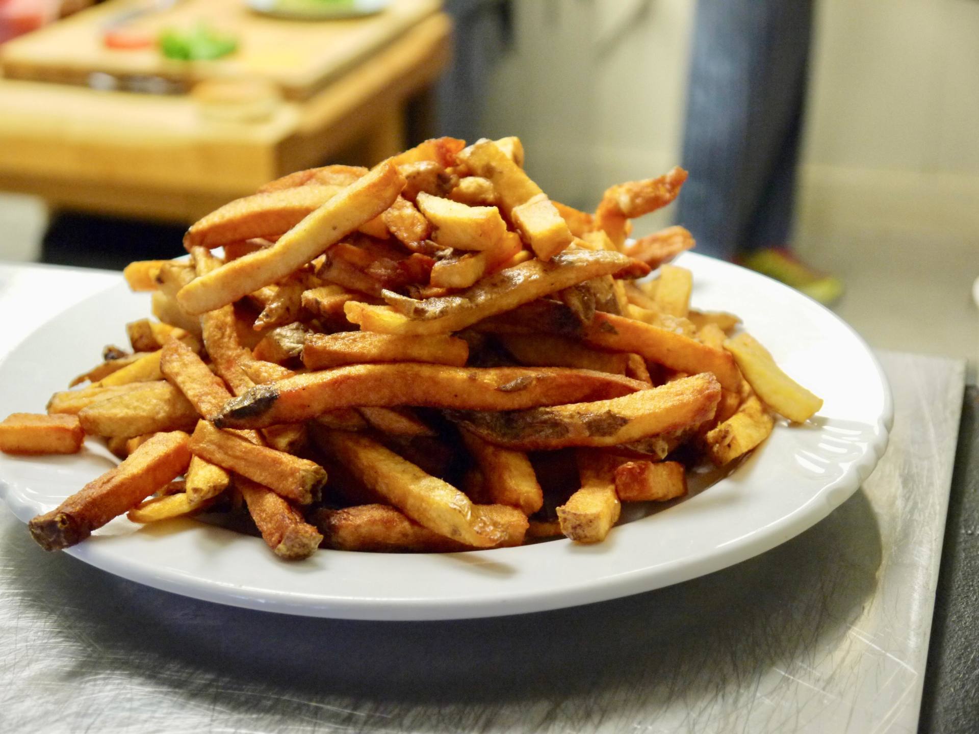 A white plate topped with french fries on a table