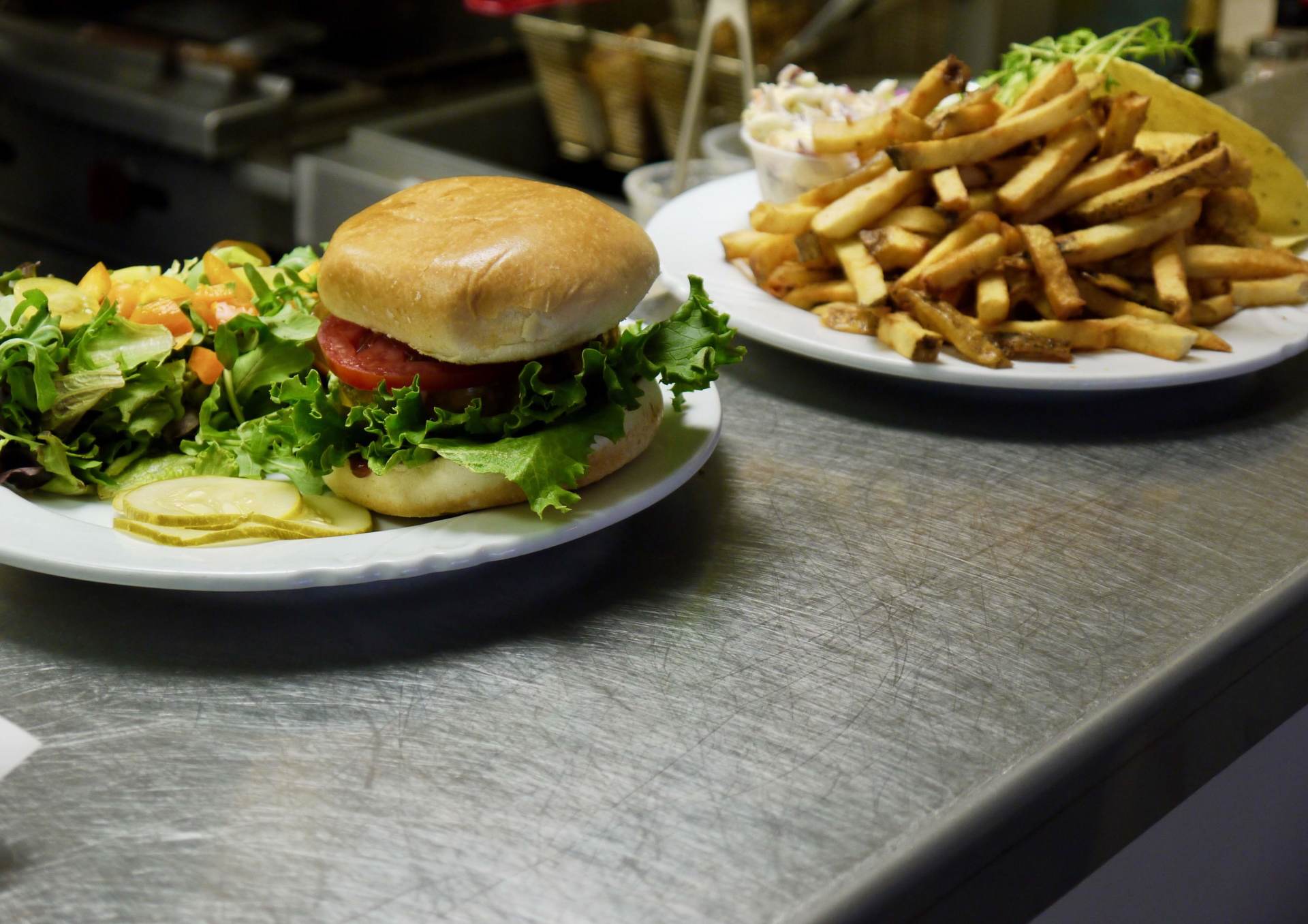 A hamburger and french fries are on plates on a counter.